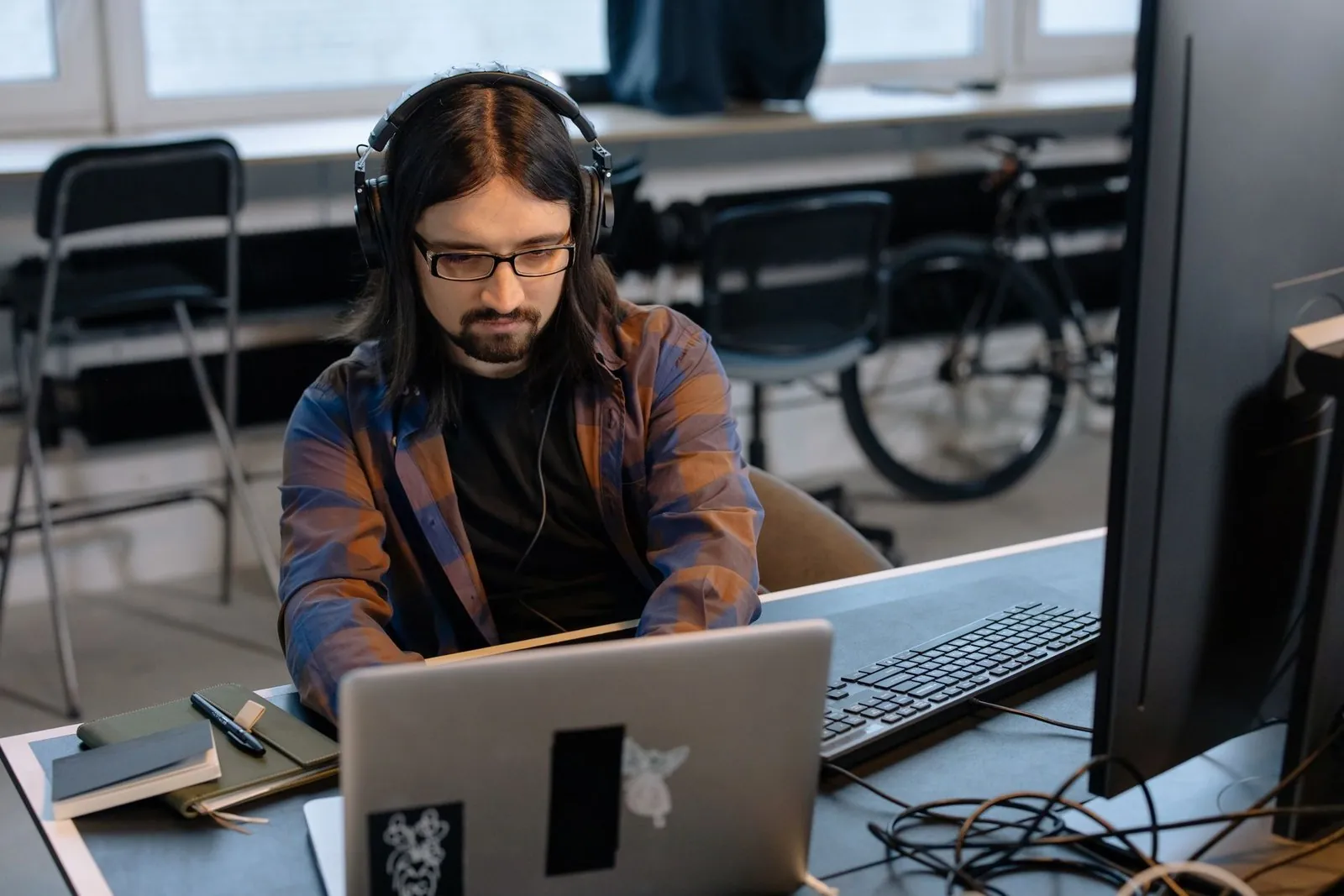 Software developer wearing headphones working at a laptop in an open office