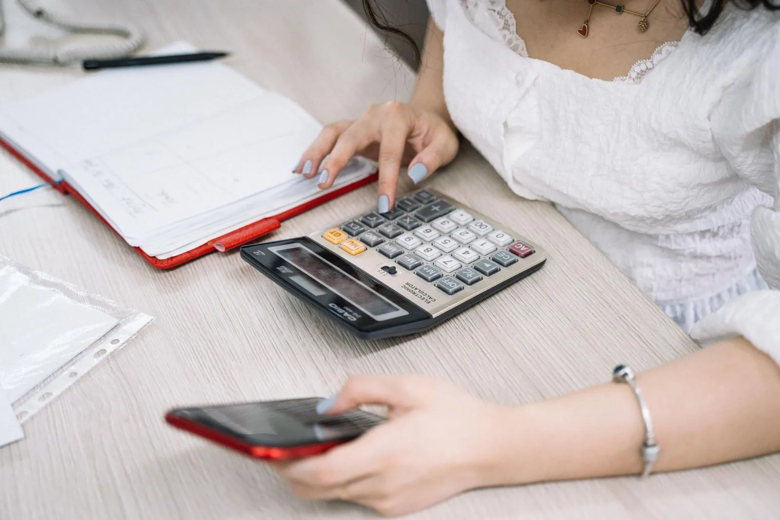 Office worker checking payroll numbers on a calculator and phone