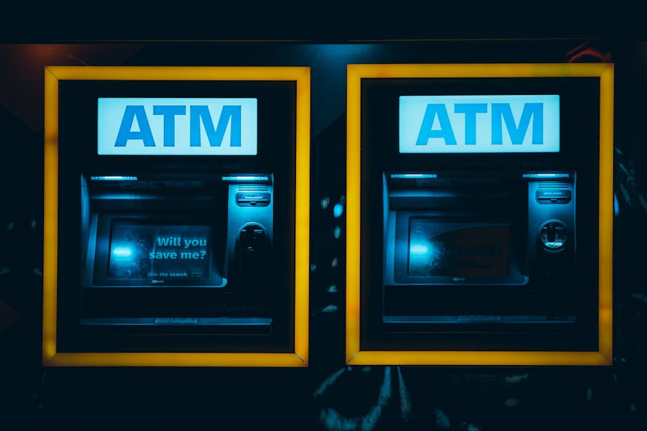 Two yellow ATM machines at night with blue ATM signs