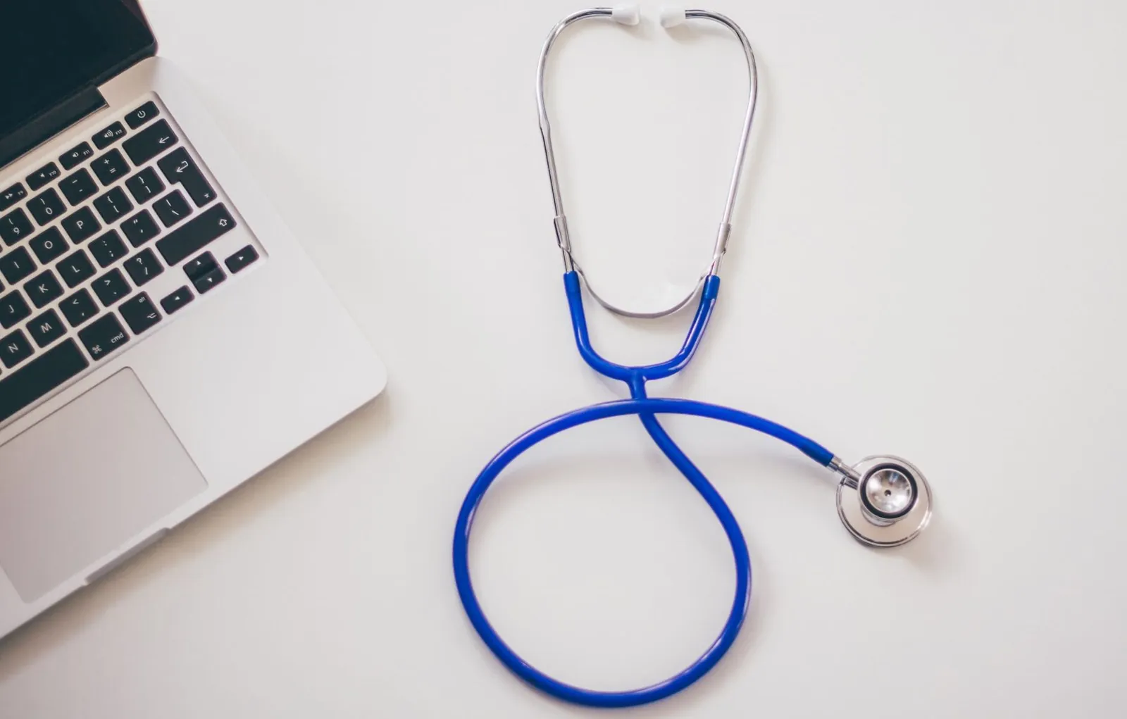 Stethoscope and laptop on a white desk
