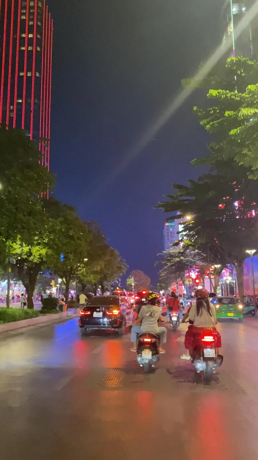 Two motorbikes riding a lit street at night