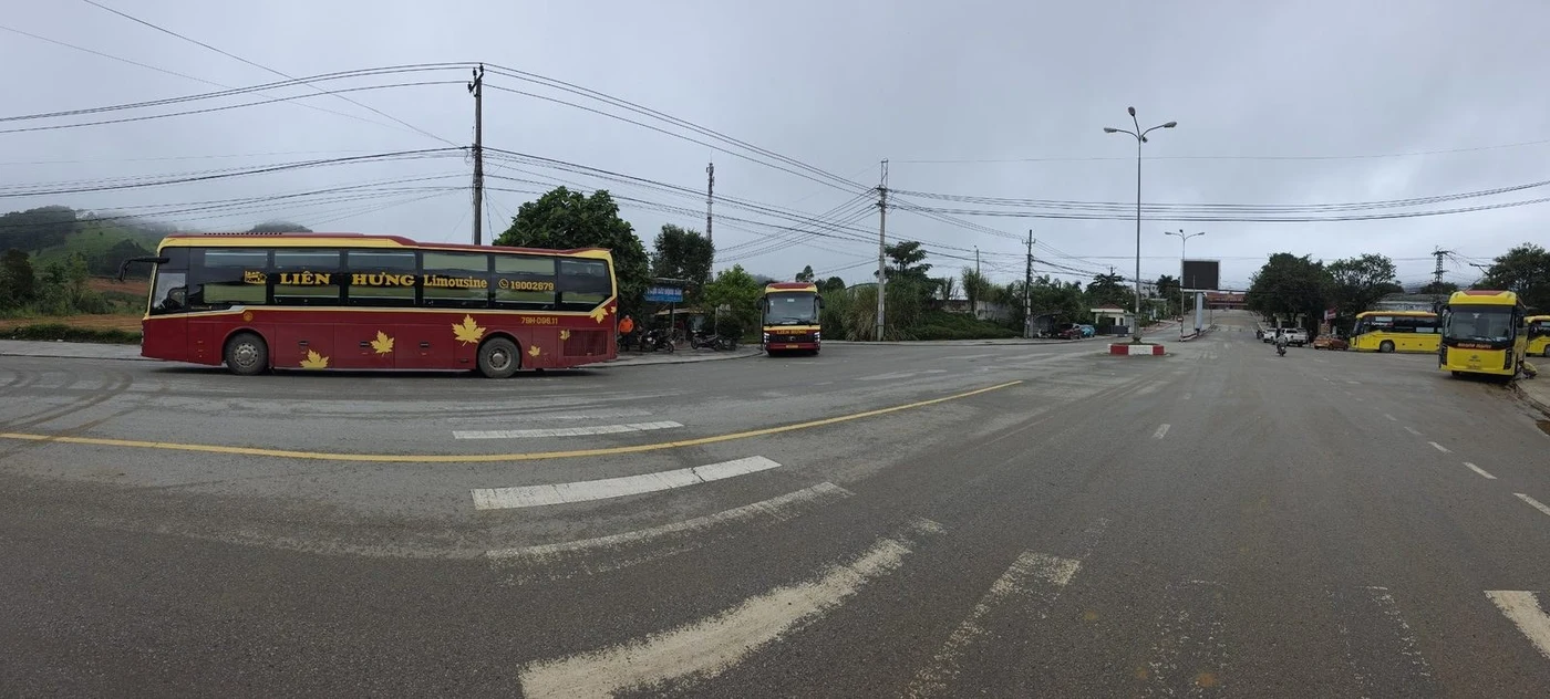 Panoramic view of a border-crossing bus parking area with mountains behind