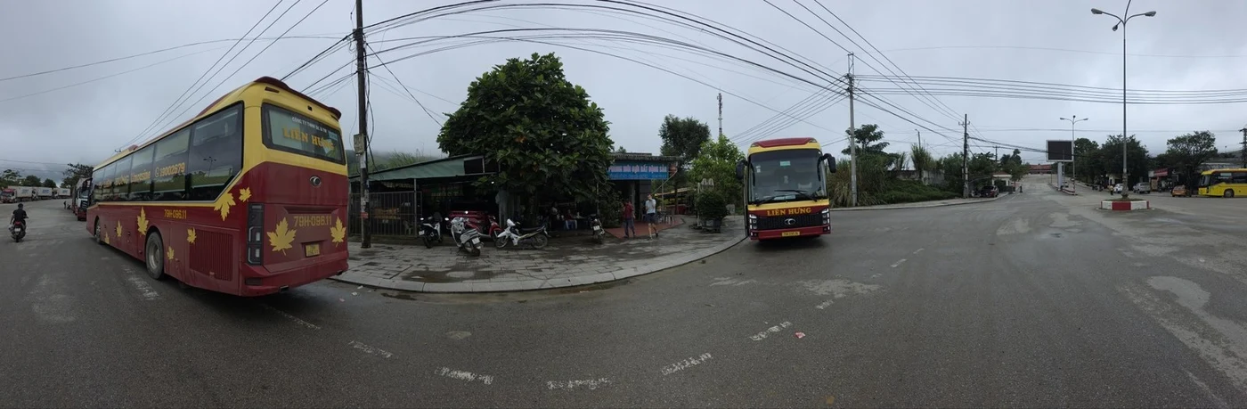 Coaches parked at a mountain border bus station under a cloudy sky