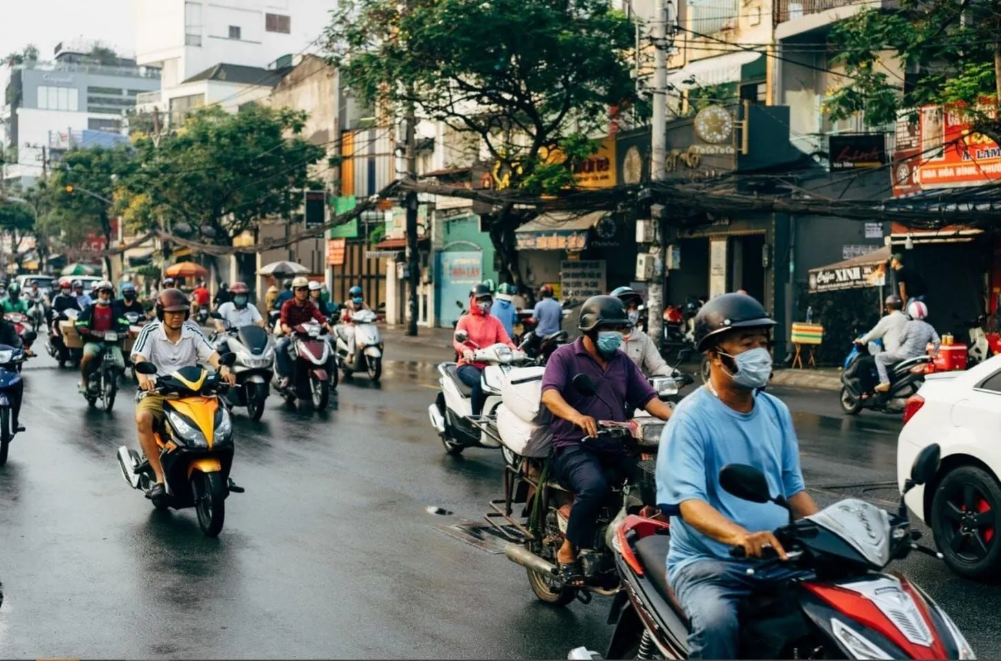 Rider on a loaded motorbike moving through a rainy Vietnamese street