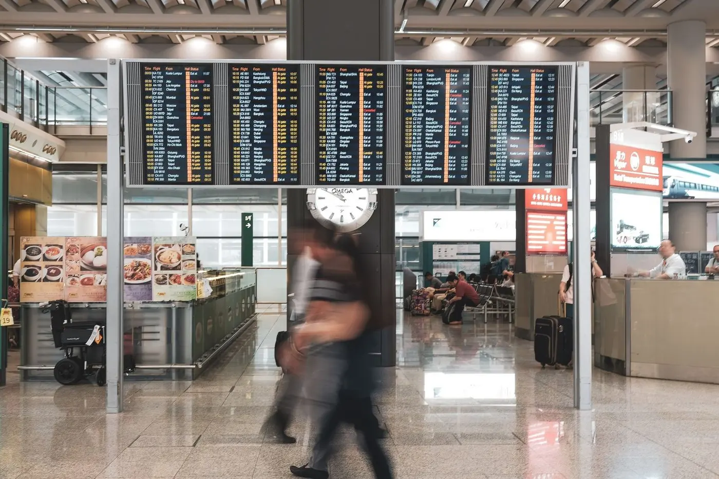 Departures board and hurrying passengers in an airport hall