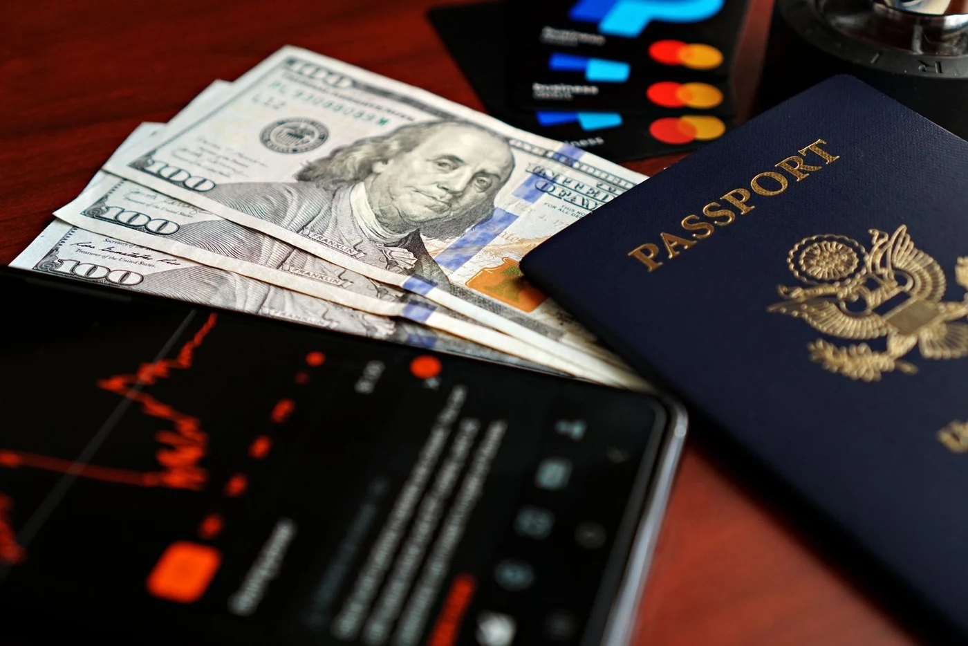 US hundred-dollar bills beside a passport, bank cards and a smartphone