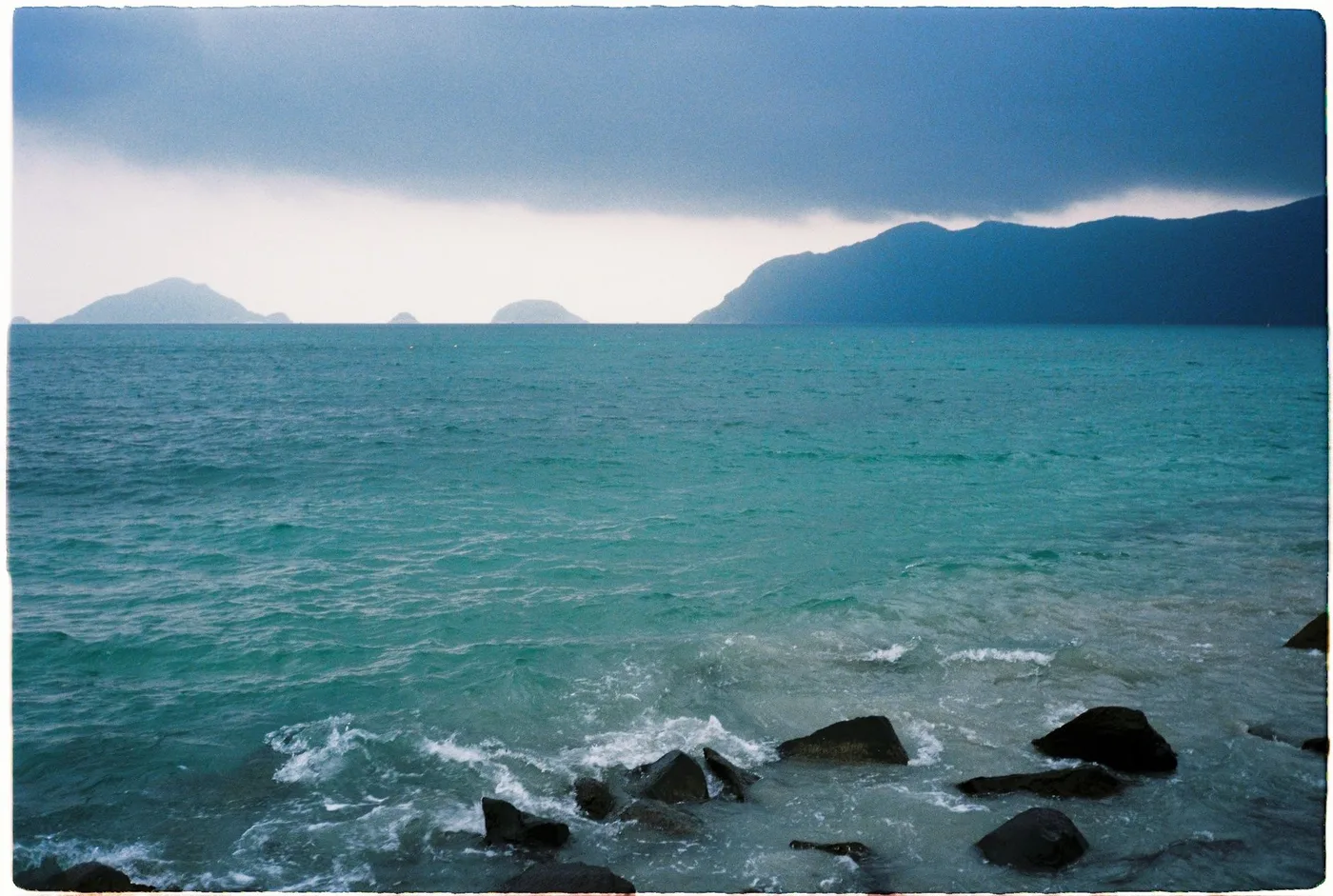 Dark storm cloud over choppy green water and islands off southern Vietnam