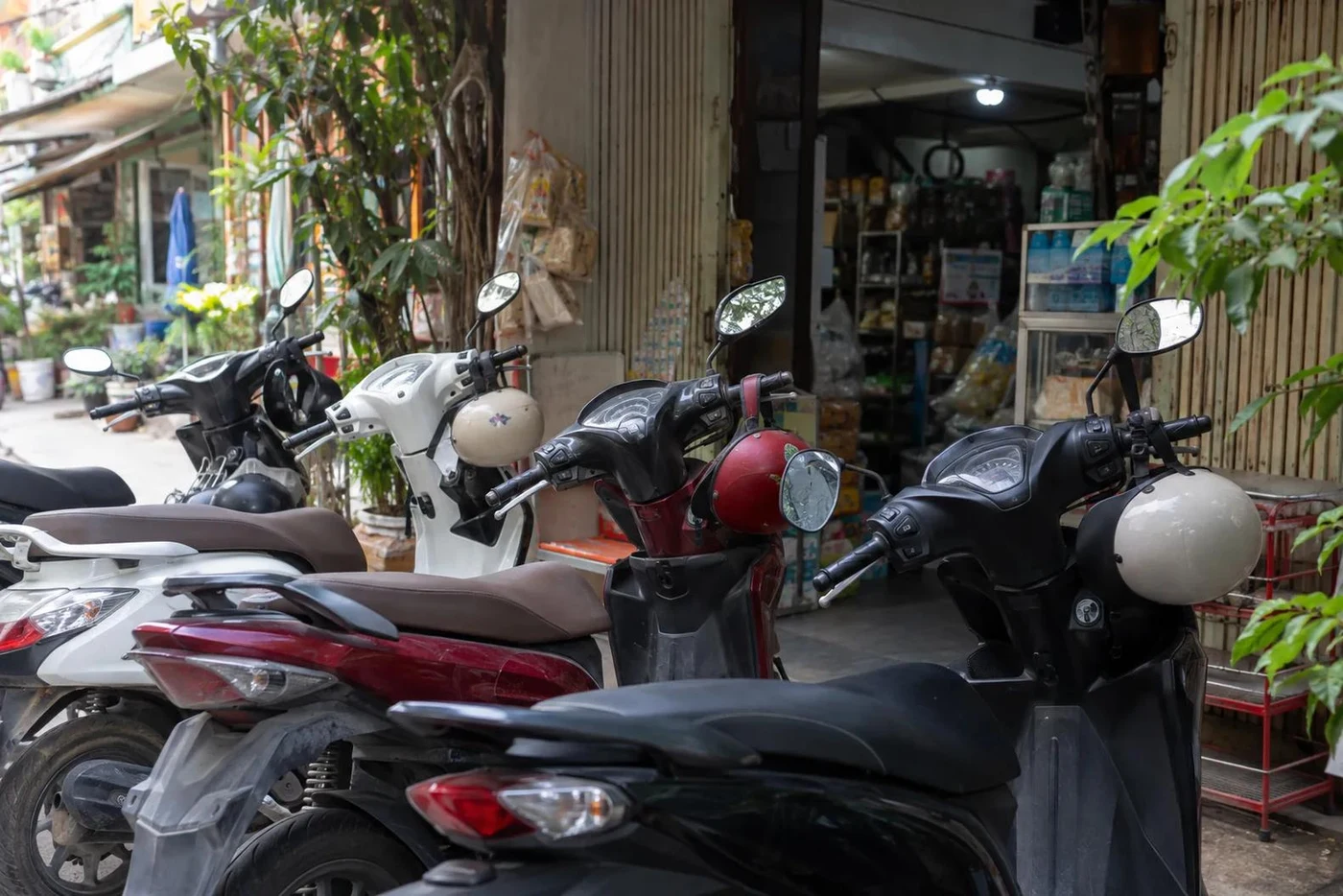 Row of parked scooters with helmets outside a neighborhood shop