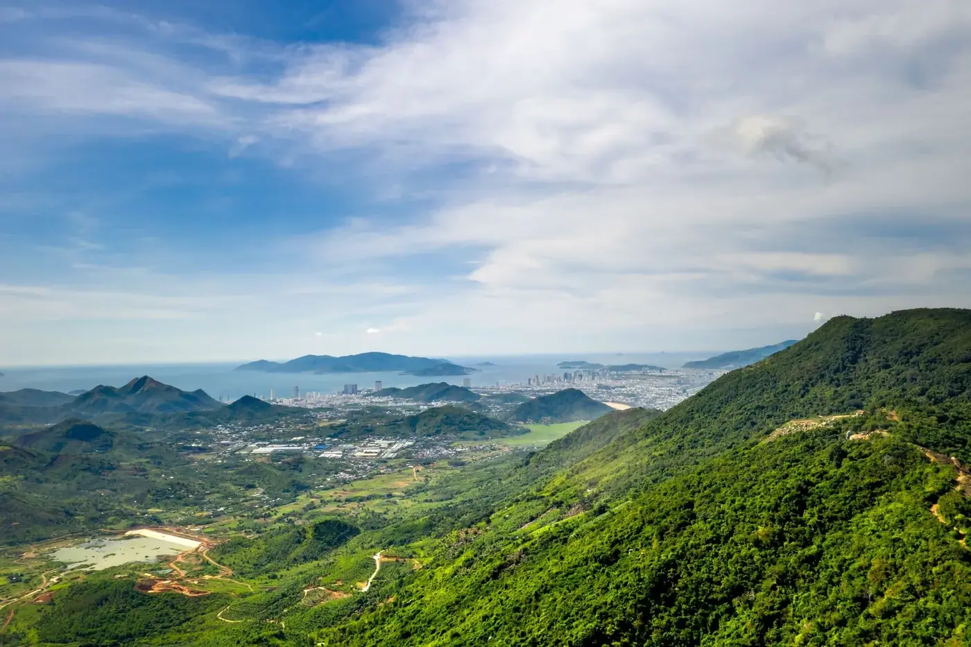 Aerial view of a mountain landscape with a coastal city in the distance