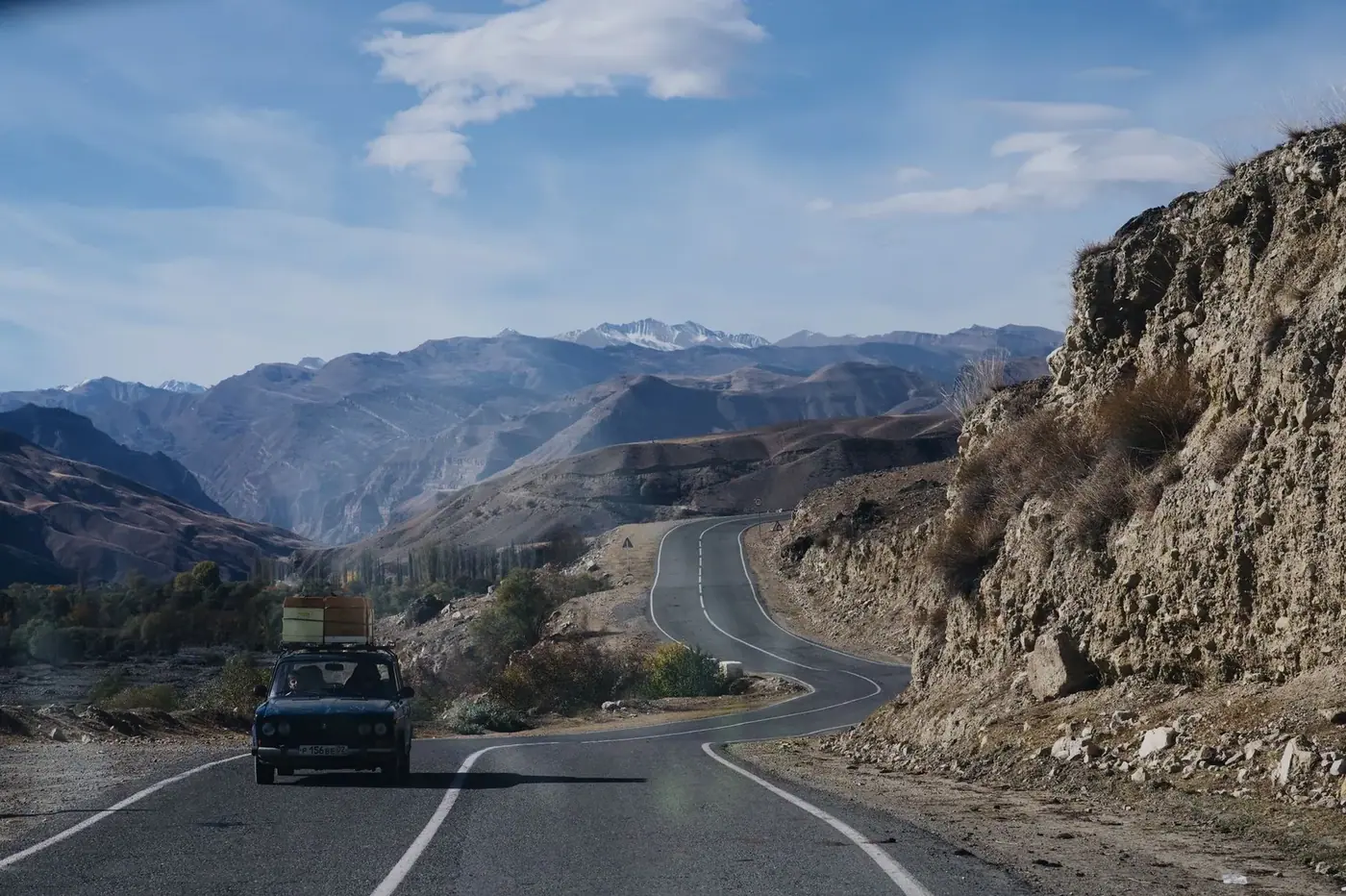 A car driving along a winding mountain road under a clear sky