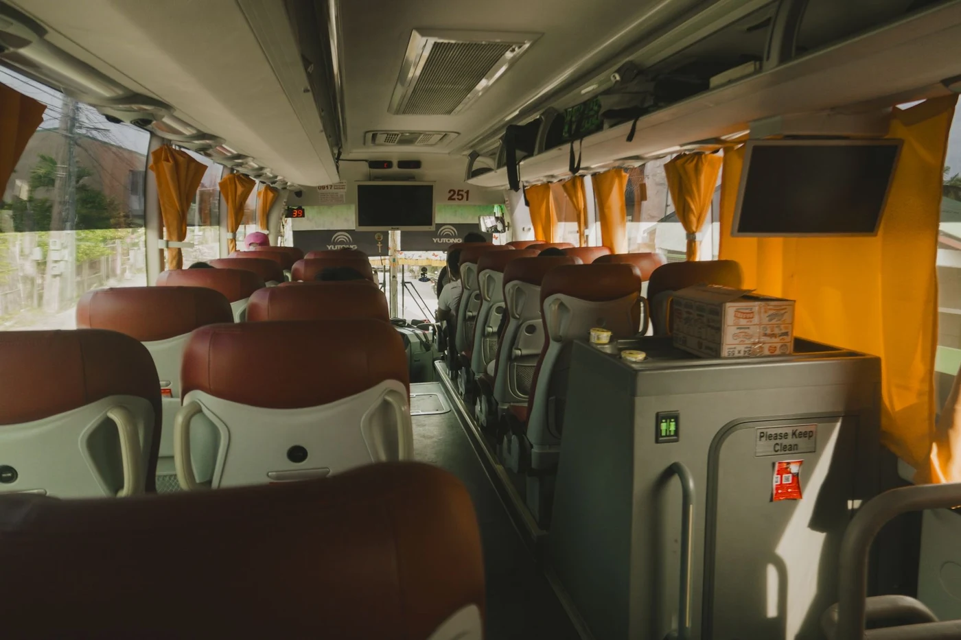 Interior of a modern coach with leather seats and an onboard toilet door marked Please Keep Clean.