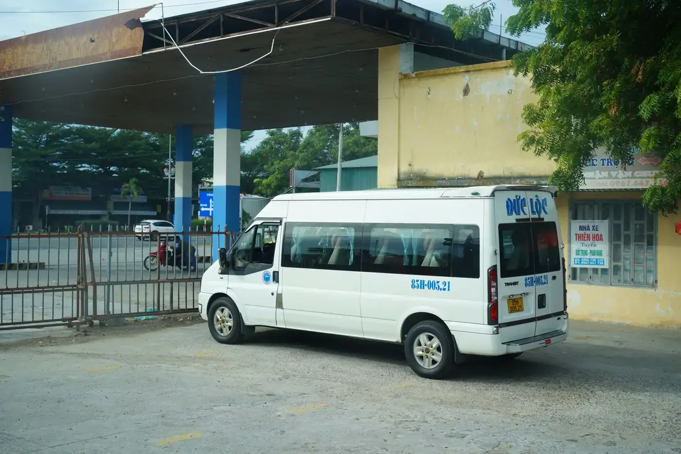 White Ford Transit limousine van parked at a highway rest stop in Vietnam