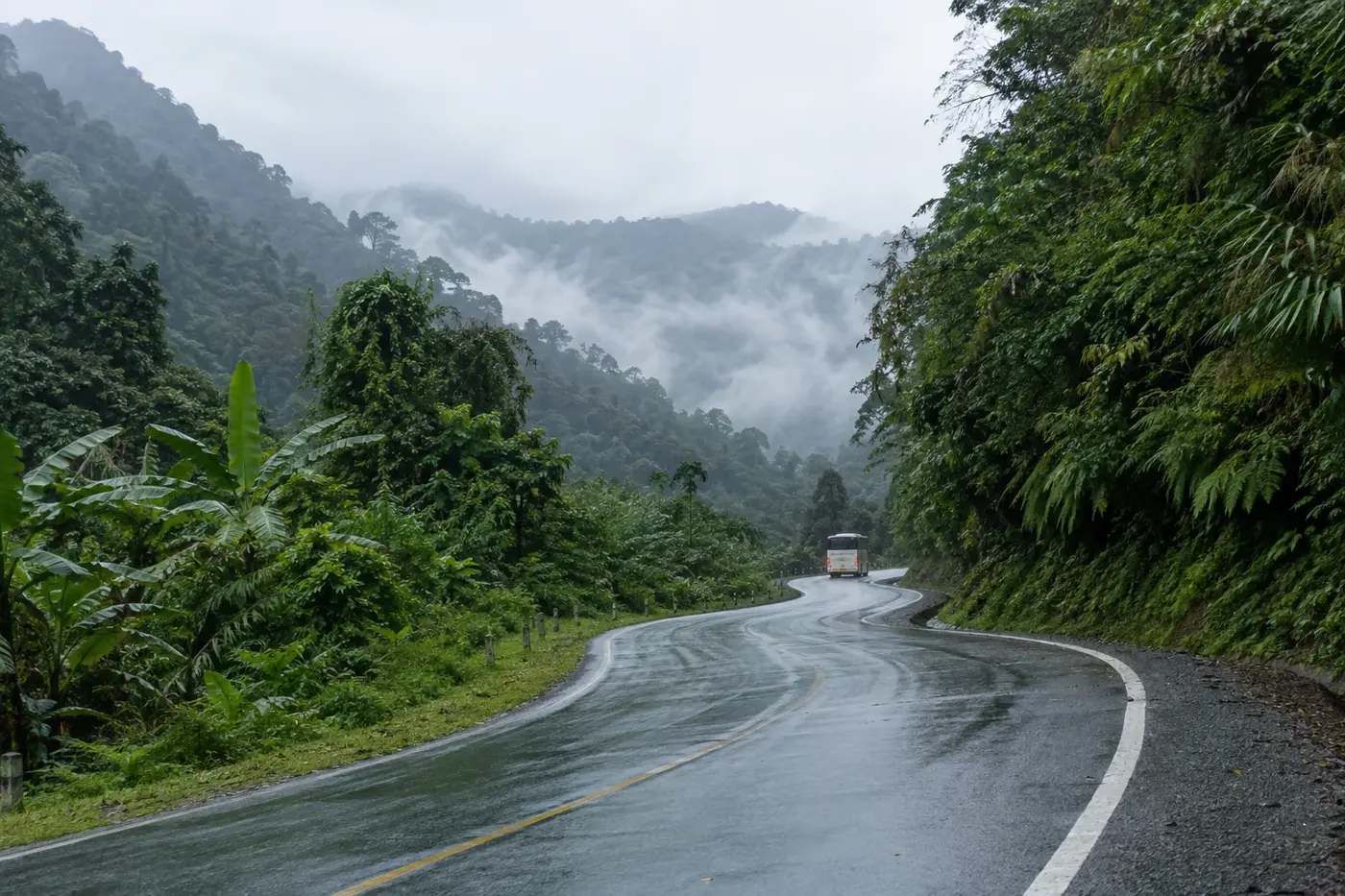 Wet mountain road with a bus in mist