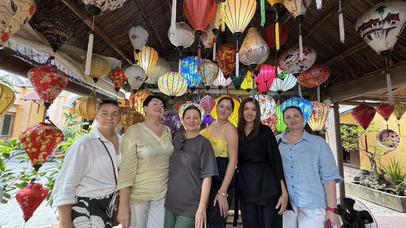 Group of visitors standing among colourful silk lanterns in a Hoi An workshop