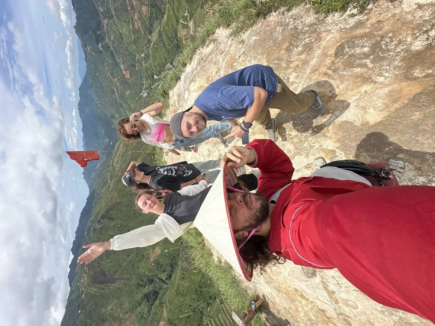 Group selfie on a Ha Giang mountain summit with a Vietnamese flag