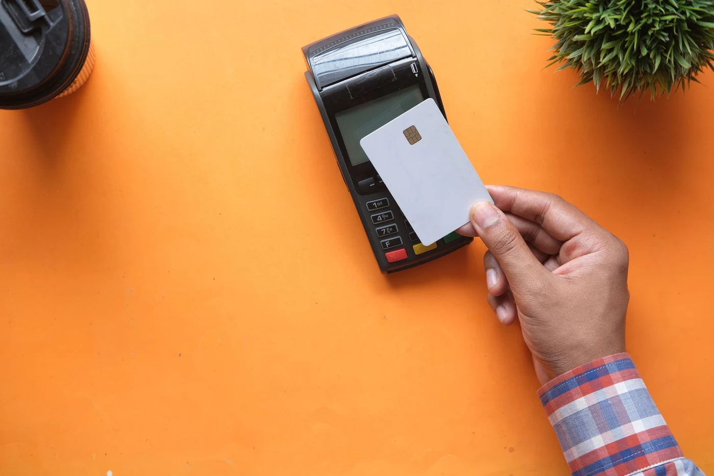 Person making a contactless card payment on a bright orange surface