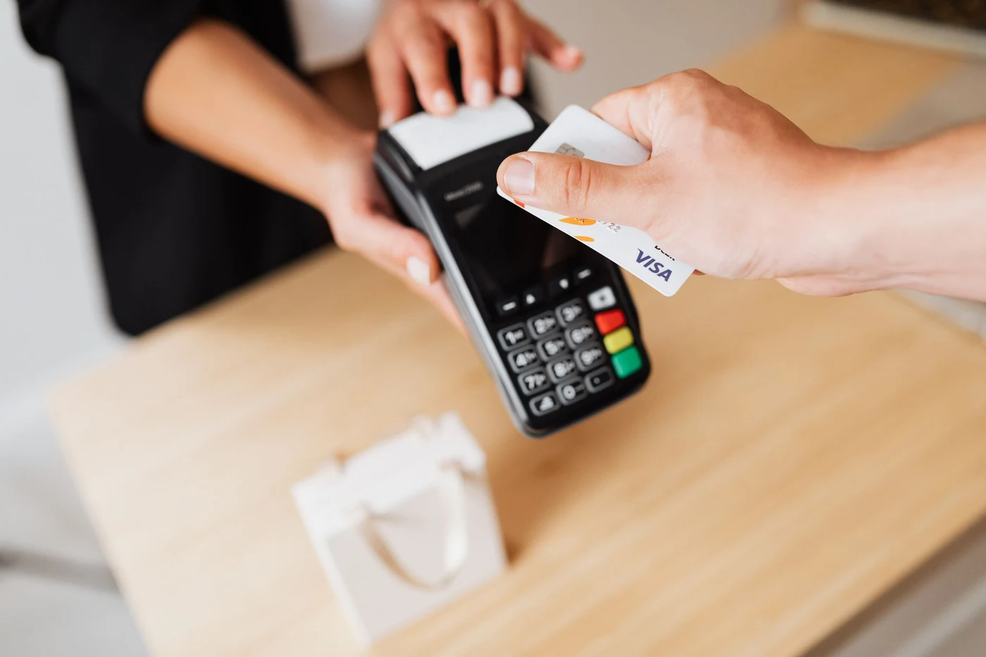 Hand tapping a bank card on a contactless payment terminal