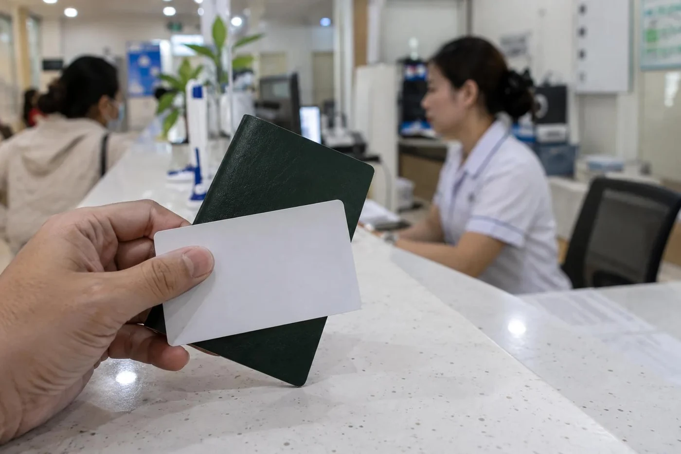 Hands holding a health insurance card and papers