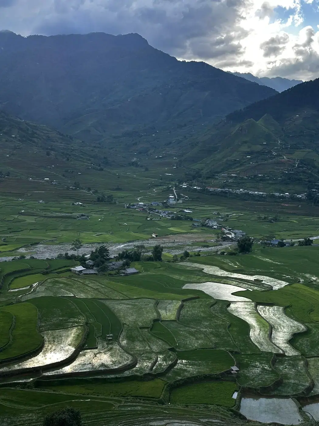 Terraced rice paddies and a river valley village under a stormy sky in northern Vietnam