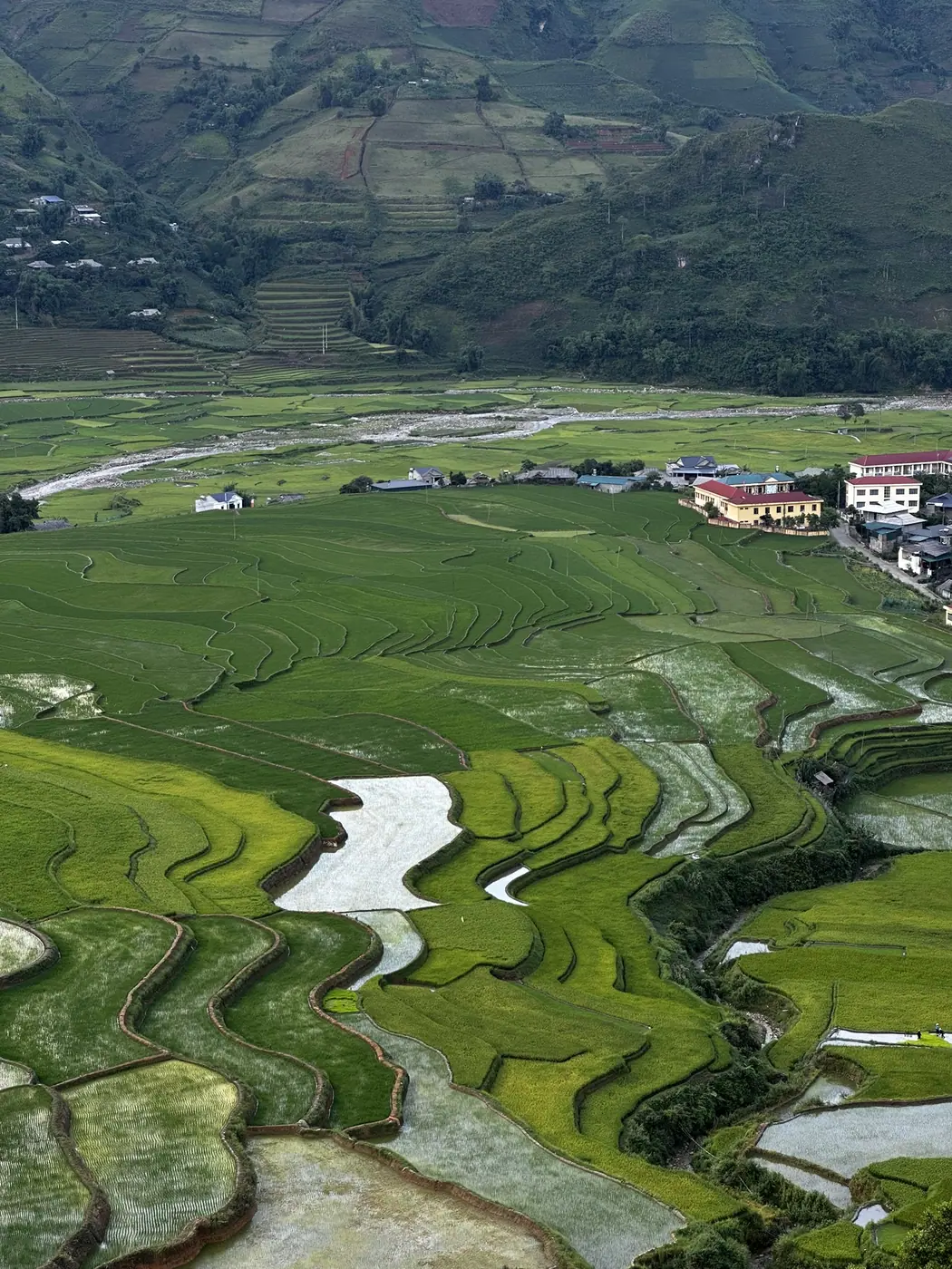 Aerial view of a river valley village surrounded by rice terraces near Moc Chau