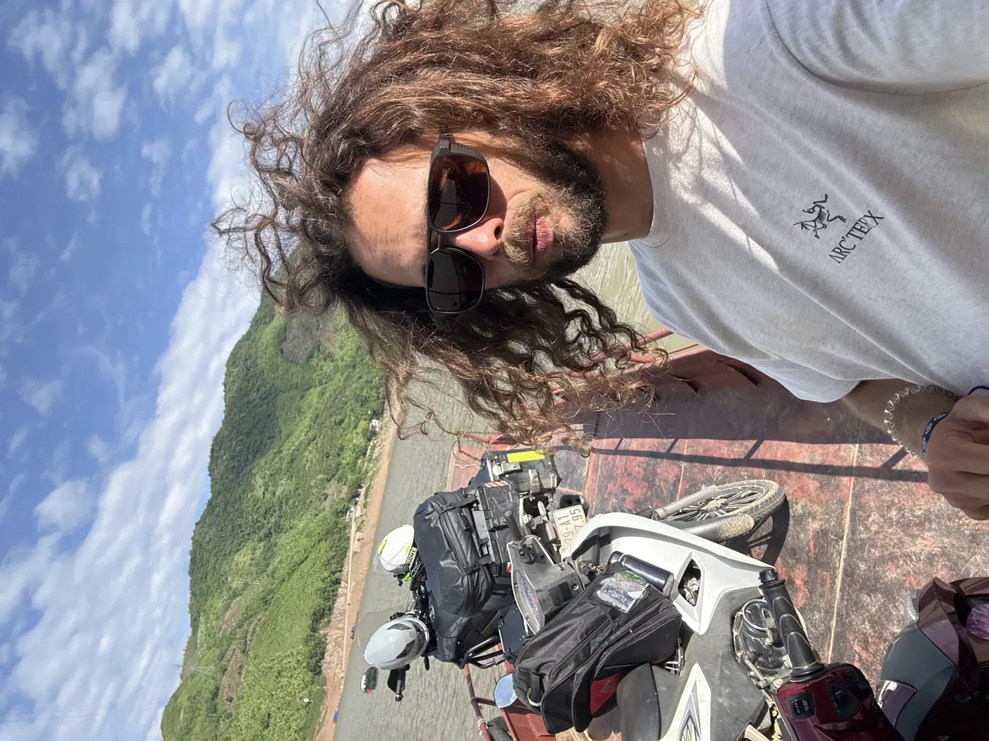Traveler on a river ferry carrying motorbikes through the mountains