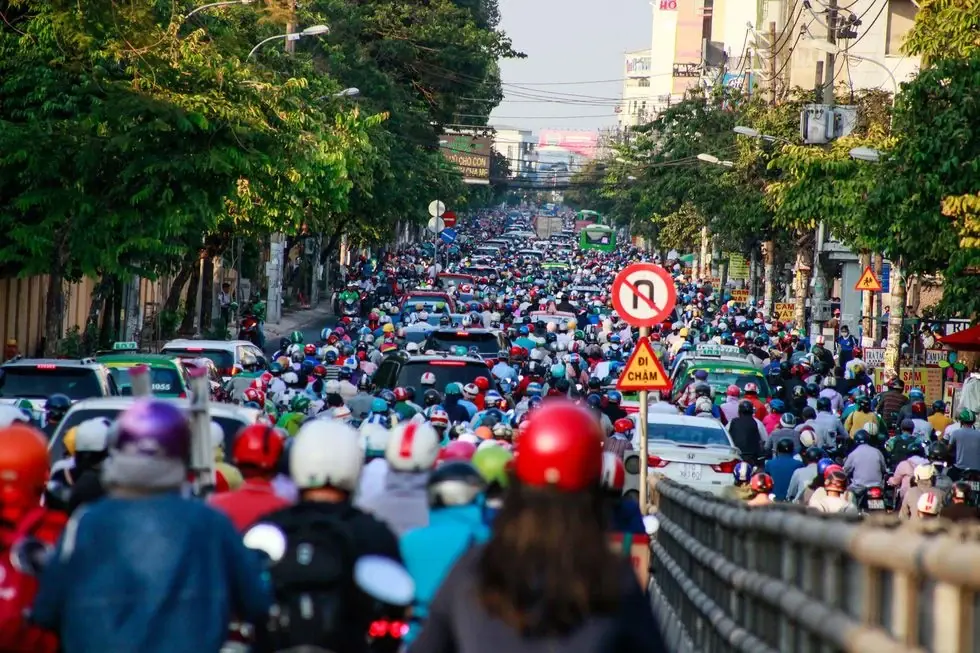 A stream of motorbikes riding down a busy street in Ho Chi Minh City