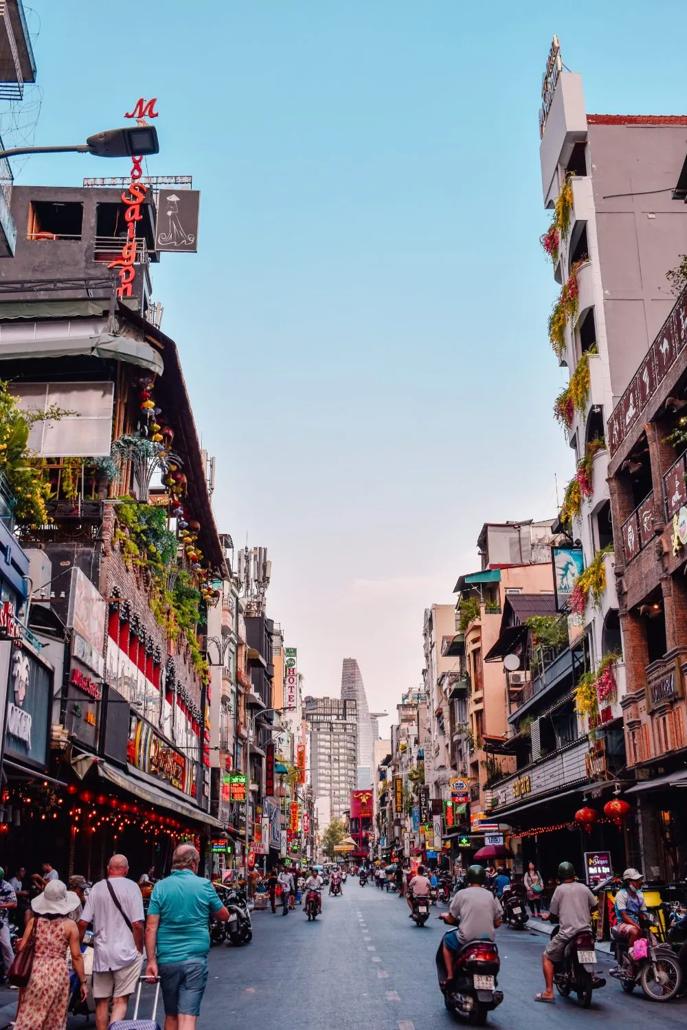 Tourists and motorbikes on Bui Vien street in Ho Chi Minh City with the Bitexco Tower behind