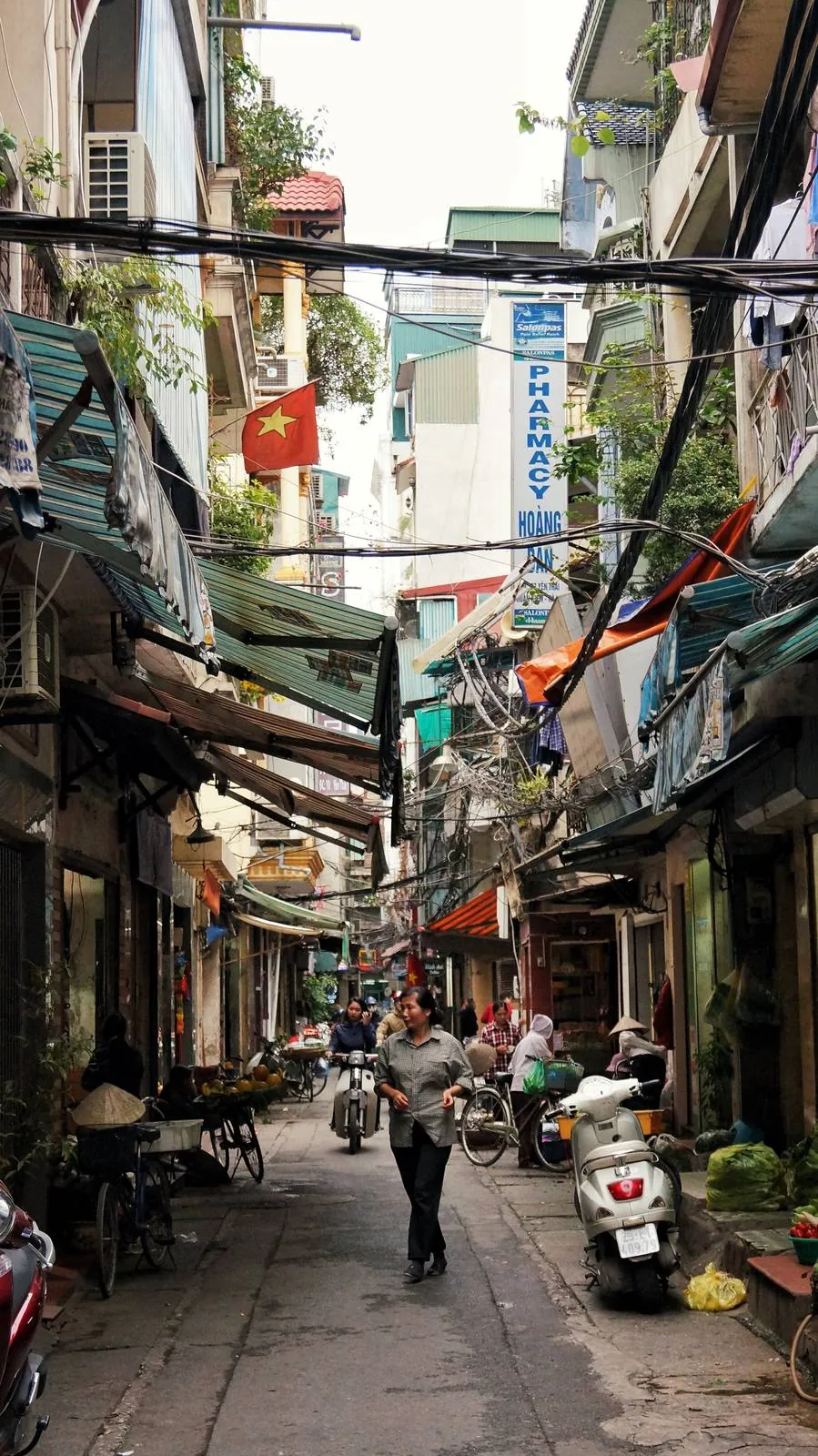A narrow Vietnamese street with a parked scooter and pedestrians