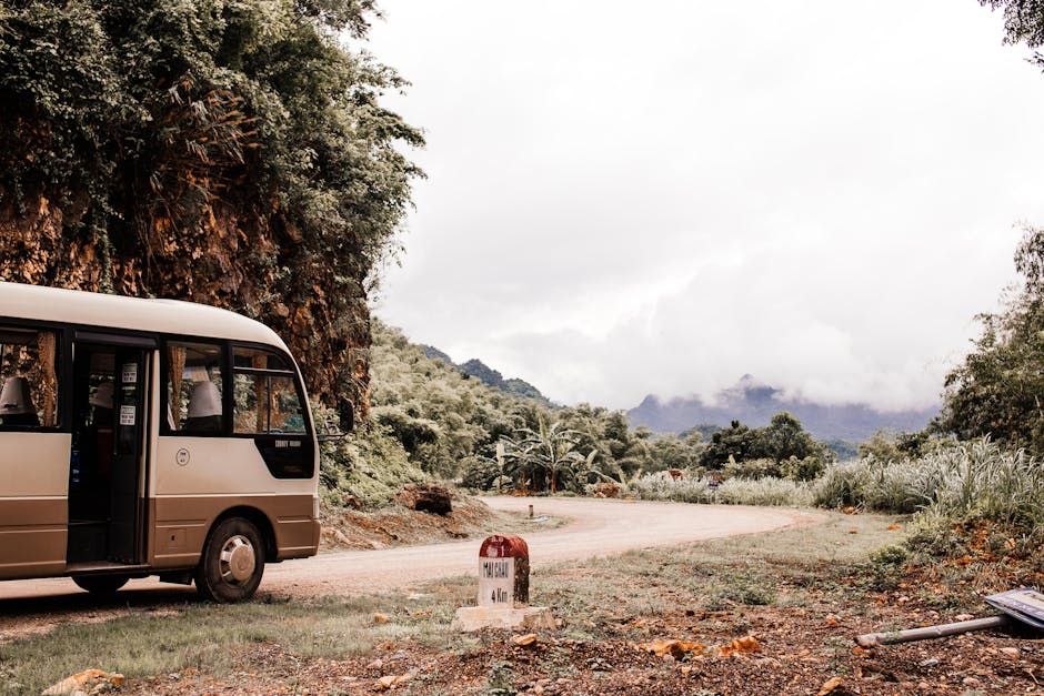 Shuttle bus parked on a winding Southeast Asian mountain road with lush forest around