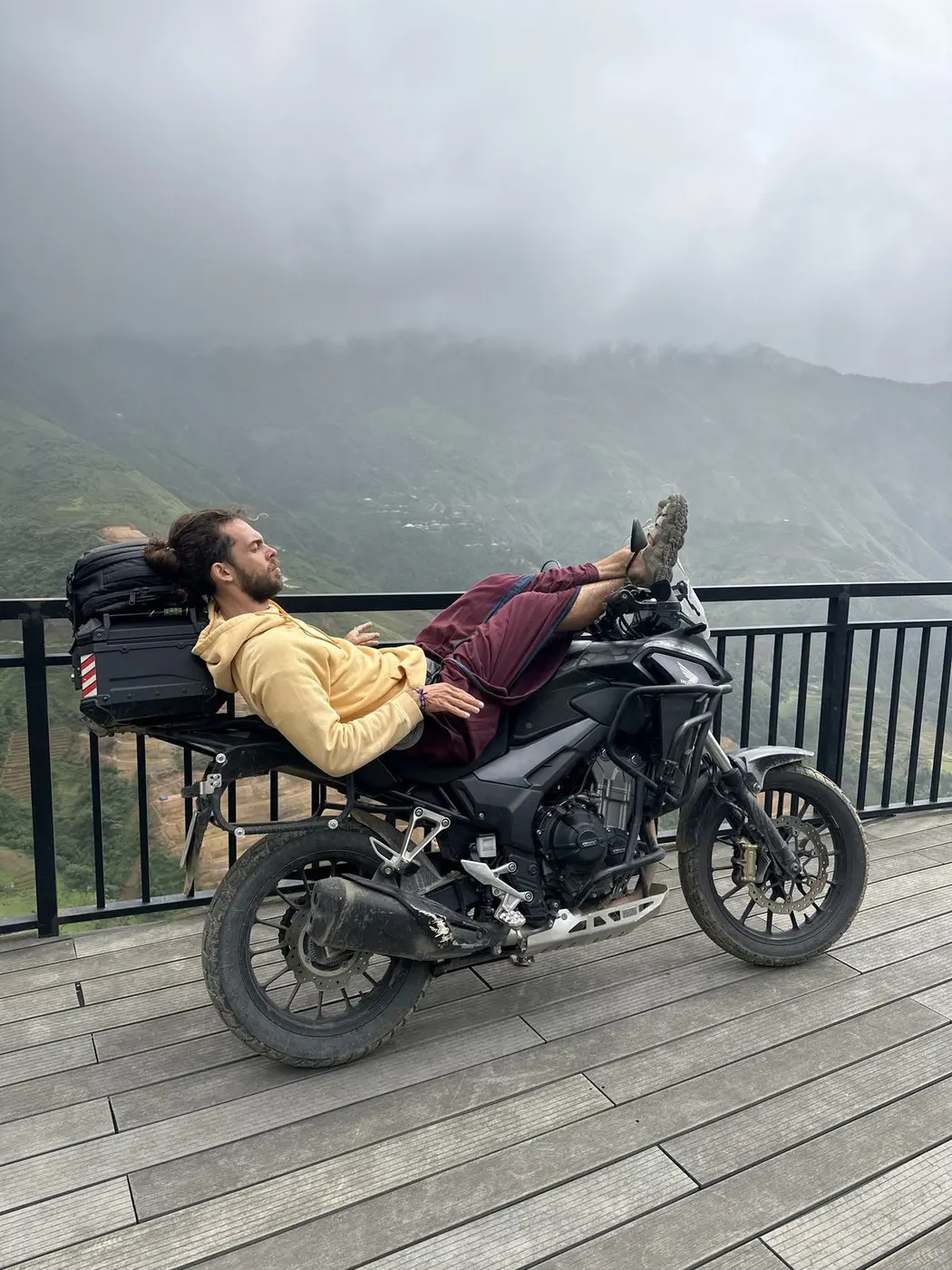 Traveler resting on a motorbike overlooking mountain terraces in northern Vietnam