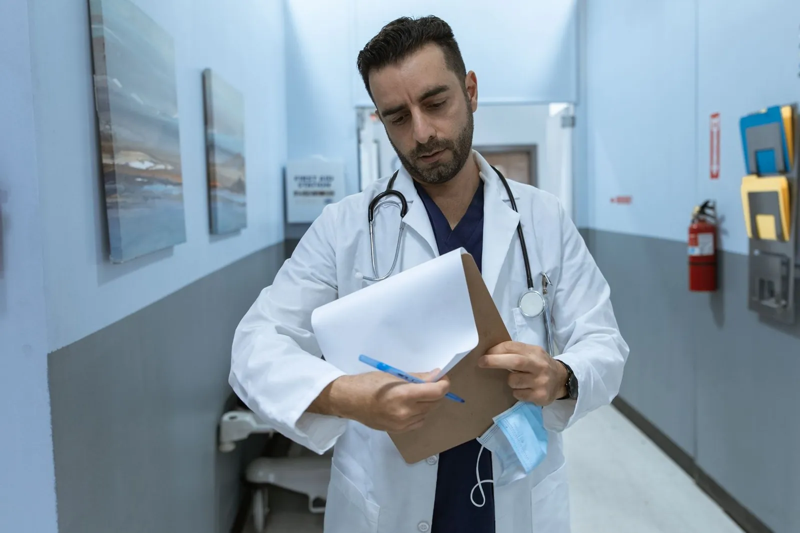 Doctor in a white coat reviewing a medical chart in a hospital hallway