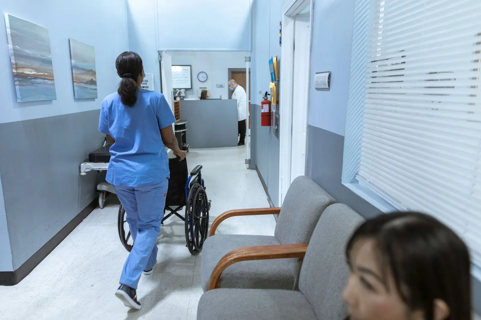 Nurse pushing a wheelchair through a hospital corridor