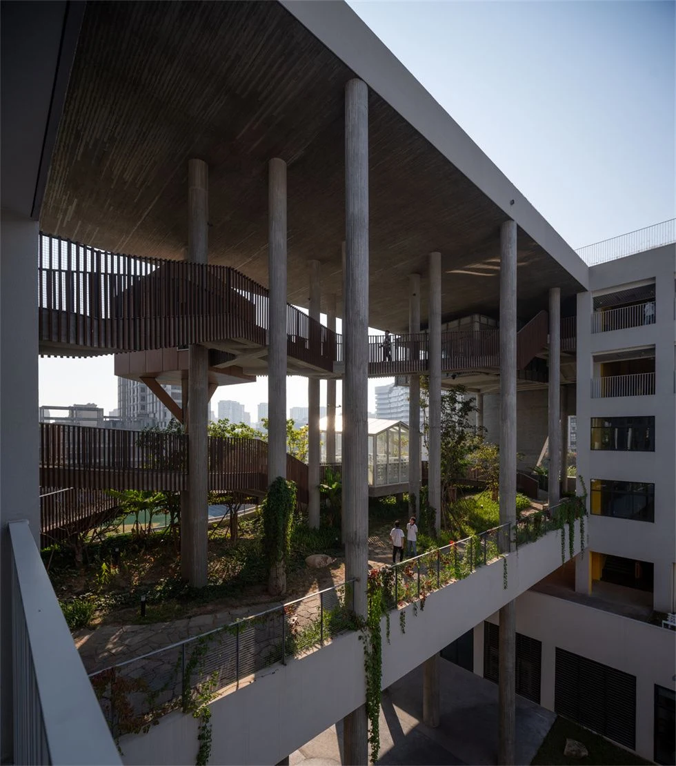 Elevated walkways and concrete columns above a school courtyard with trees