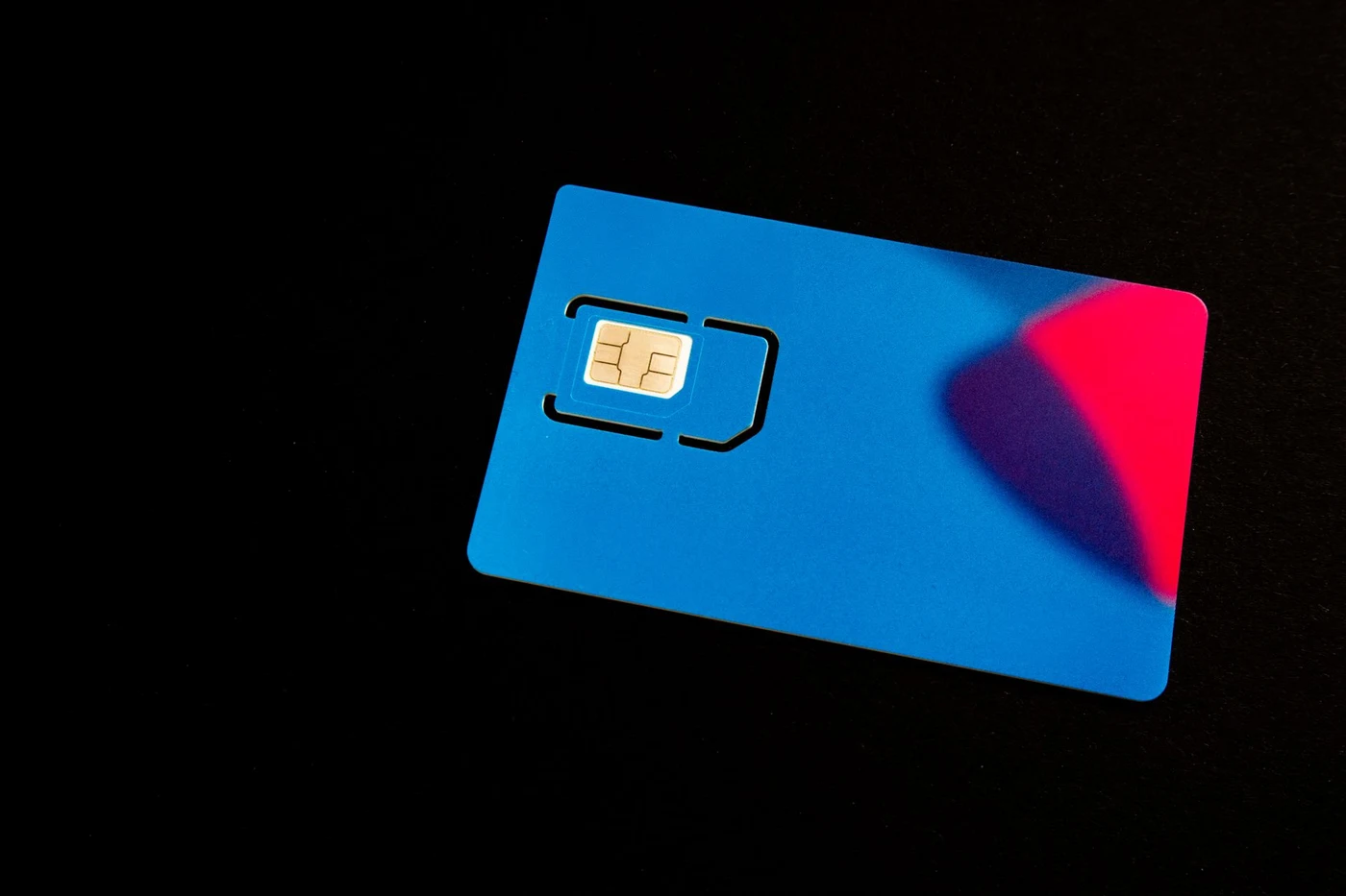 A blue SIM card in its plastic carrier on a black background