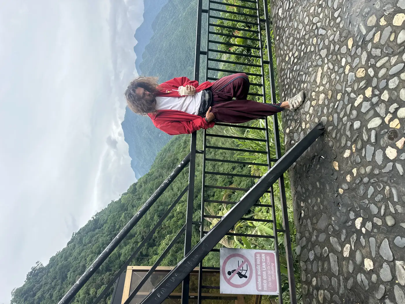 Traveler leaning on a mountain railing above clouds in Sapa