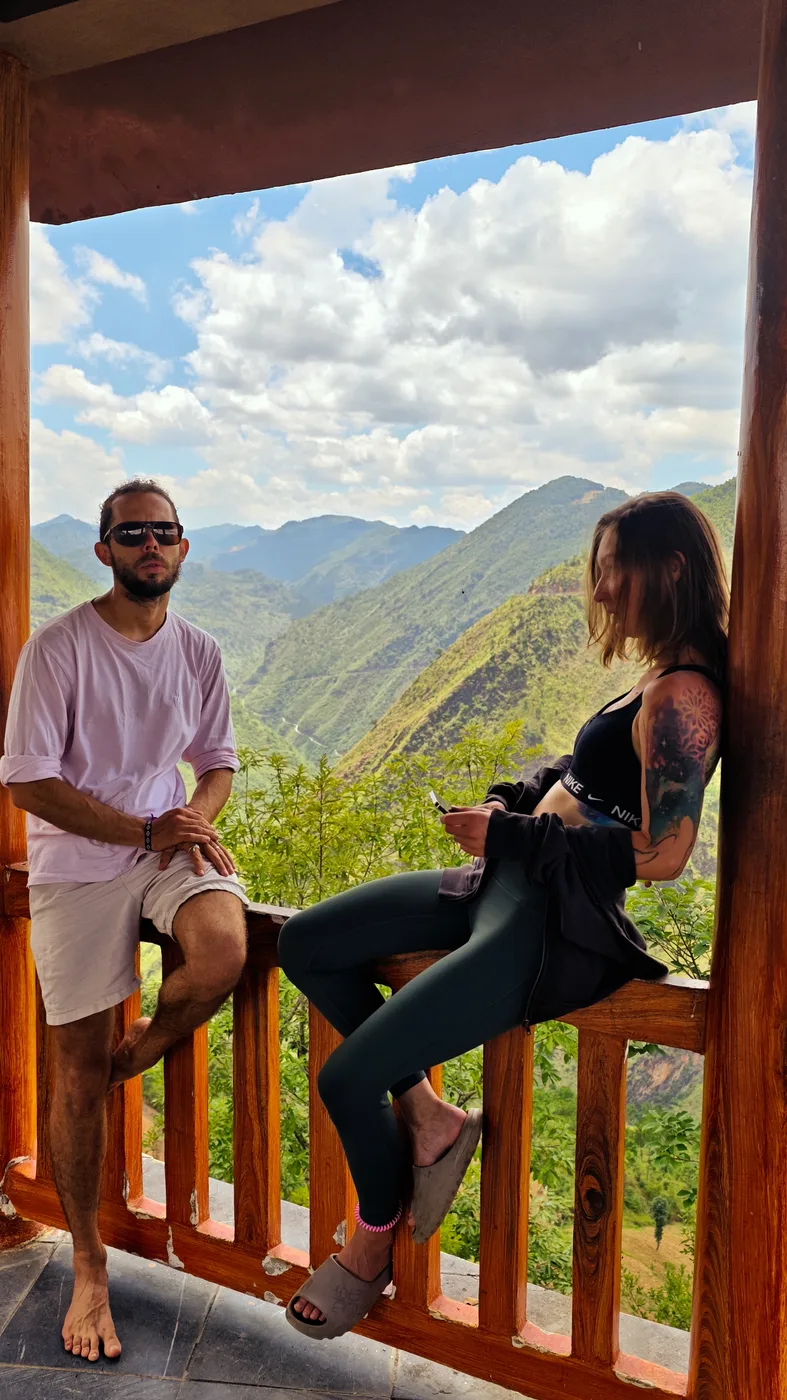 Couple relaxing on a wooden balcony overlooking a green mountain valley