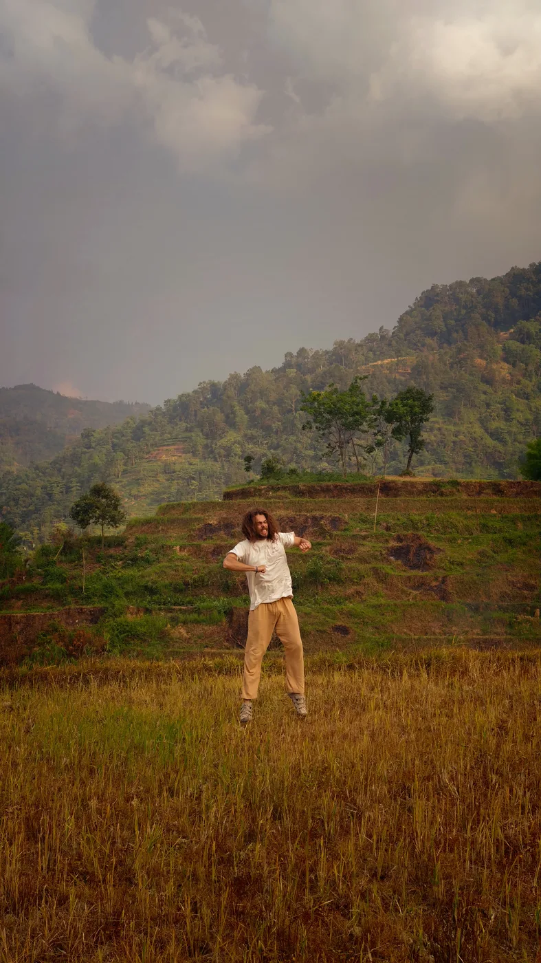 Traveler jumping mid-air on a hillside above golden rice terraces