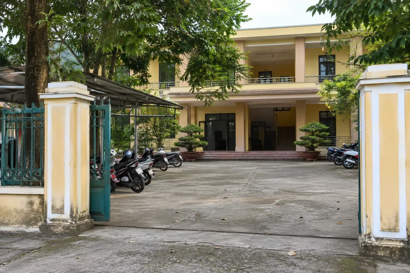 Yellow government office building with scooters parked in the courtyard