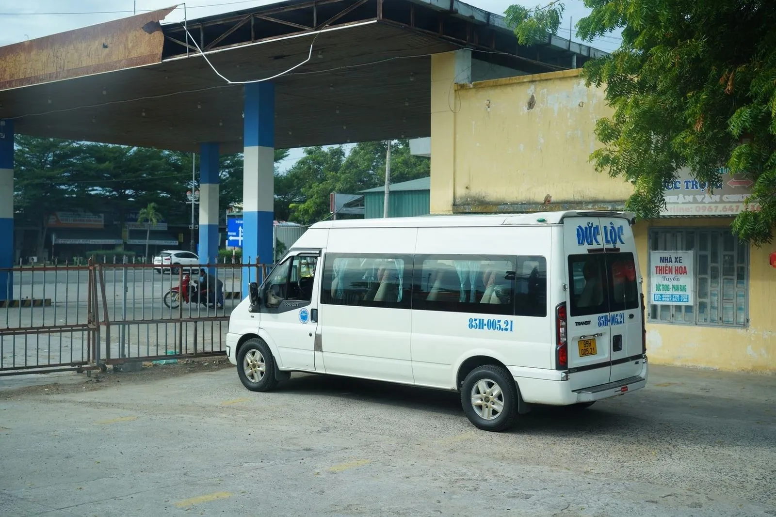 White shuttle van parked at a Vietnamese bus station