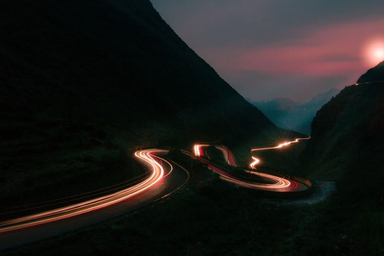 Long exposure of headlights winding through a mountain pass at night