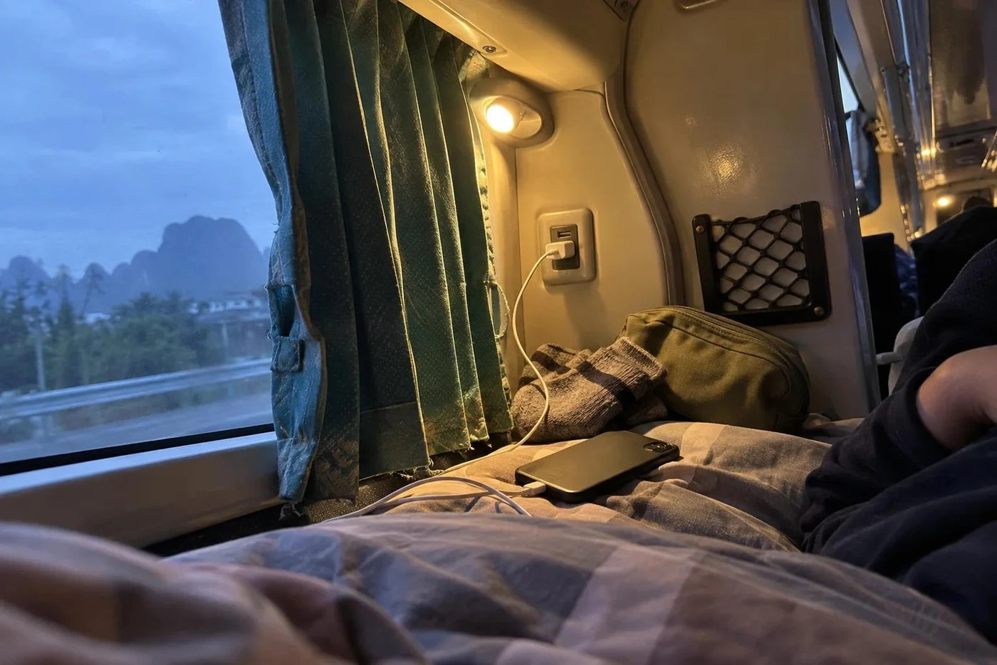 Phone charging from a USB port beside a sleeper bus berth