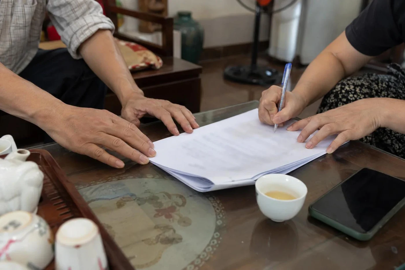 Two people signing a rental contract at a table with tea cups