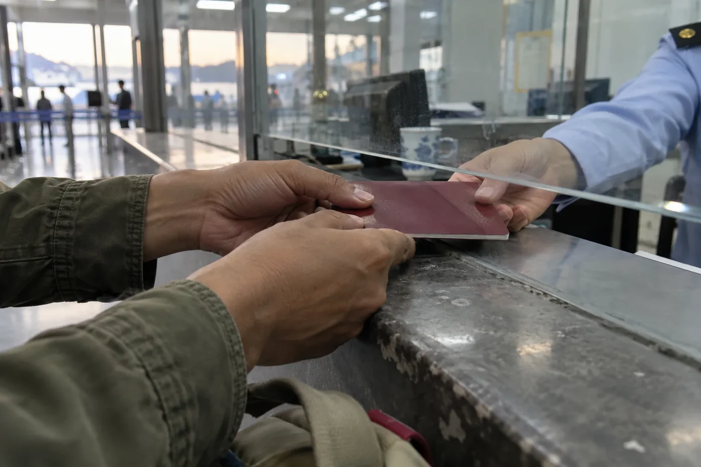A passport being passed through a counter window
