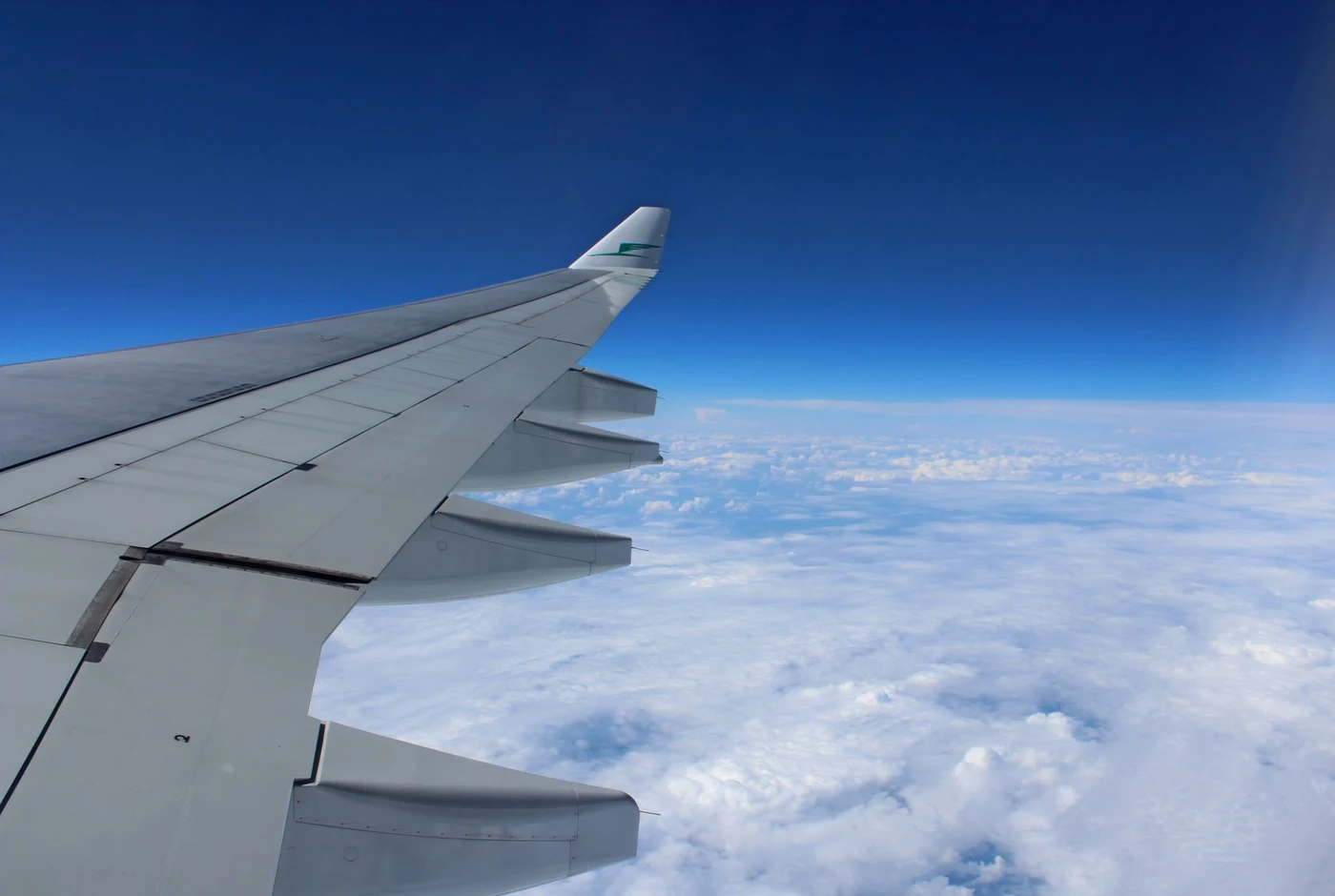 Airplane wing above clouds seen through a cabin window