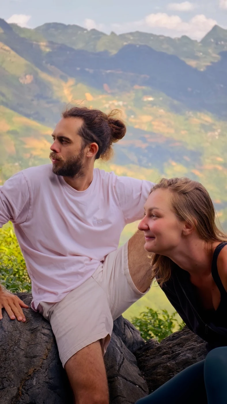 Couple resting on rocks with mountain valley view in Ha Giang