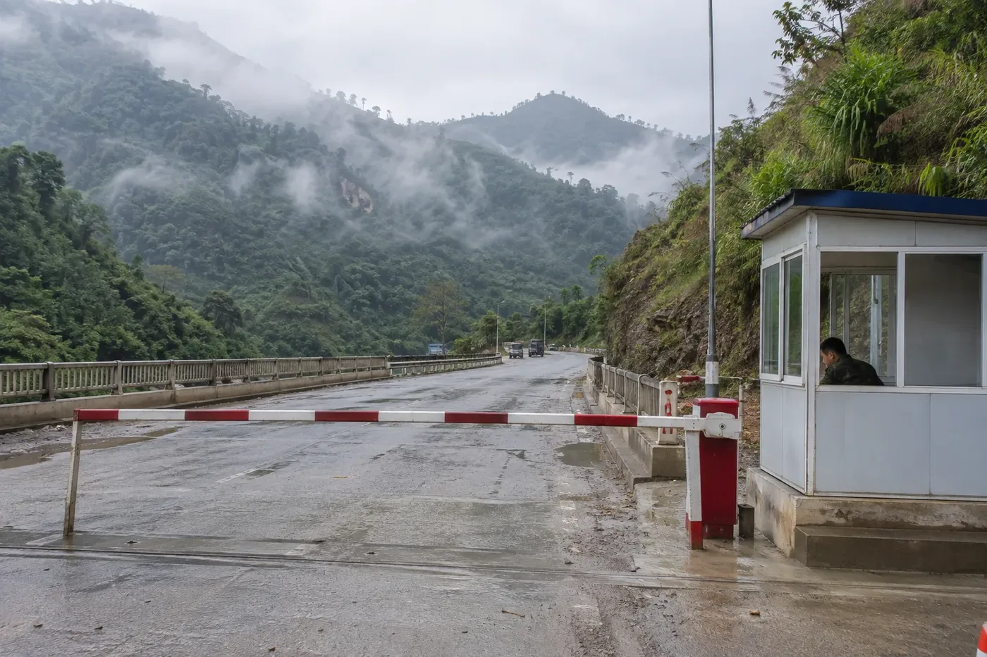 Barrier and guard booth at a mountain land border crossing in the mist