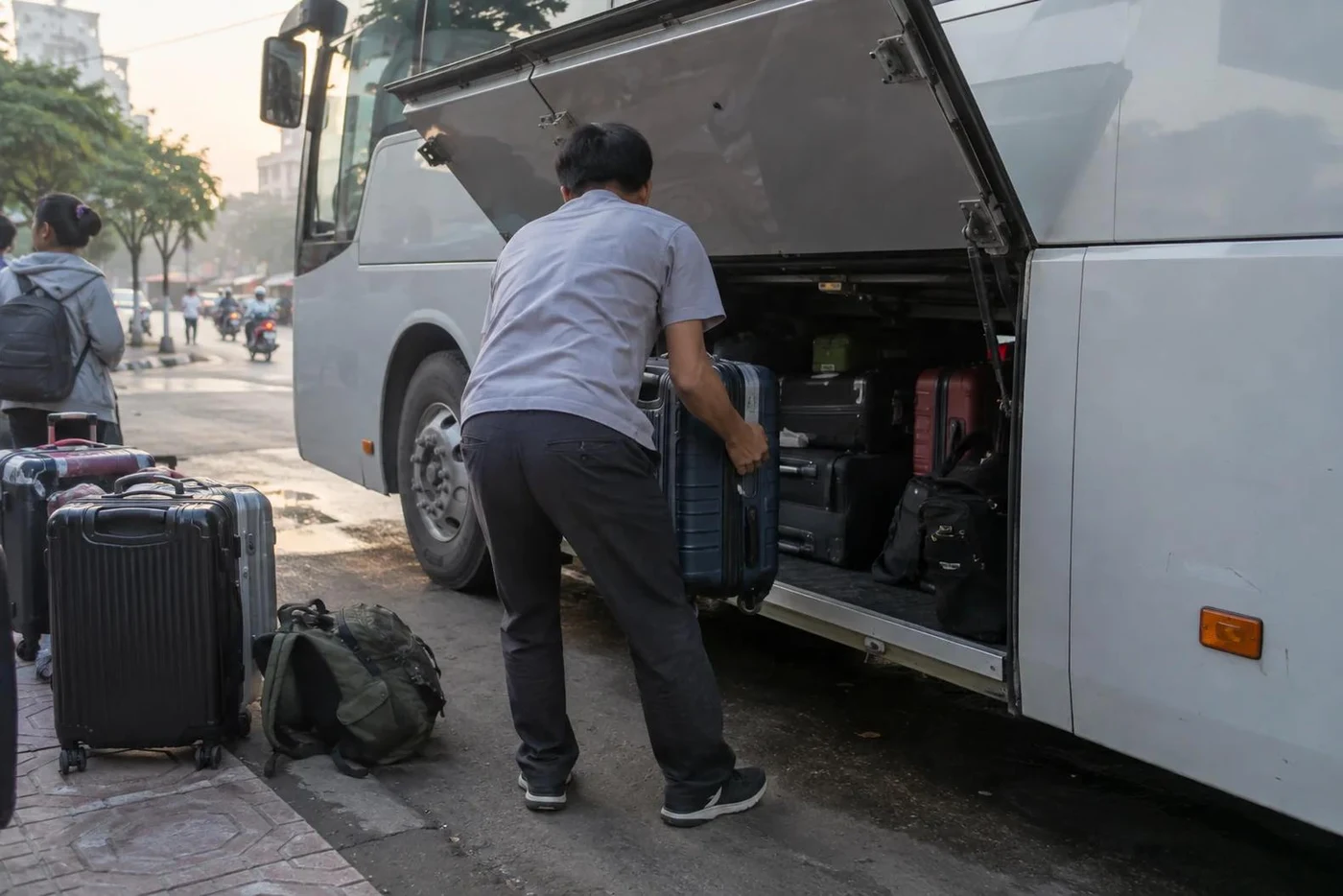 Bus attendant lifting a suitcase into the underfloor luggage hold