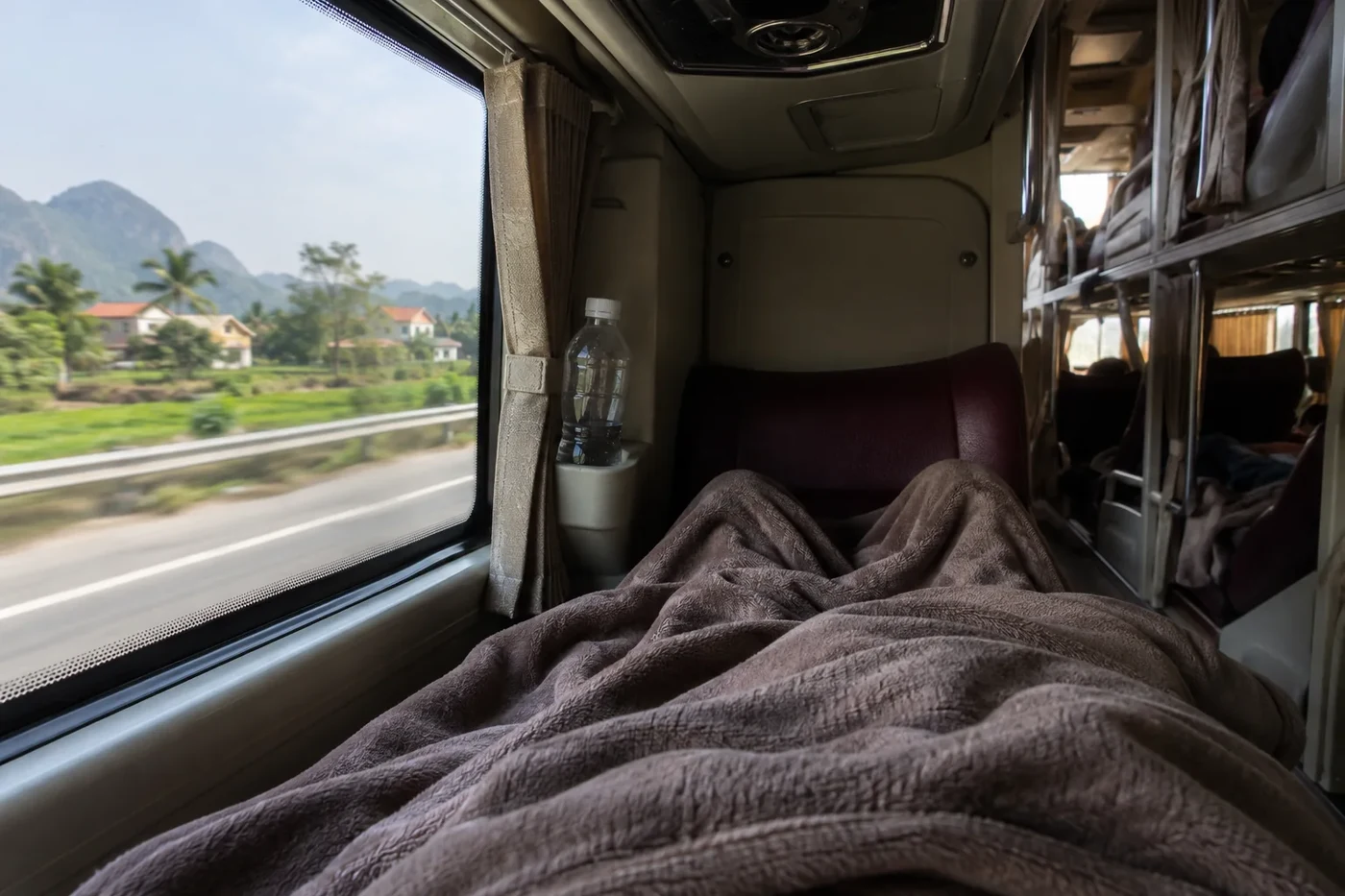 Blanket and water bottle on a berth next to the bus window