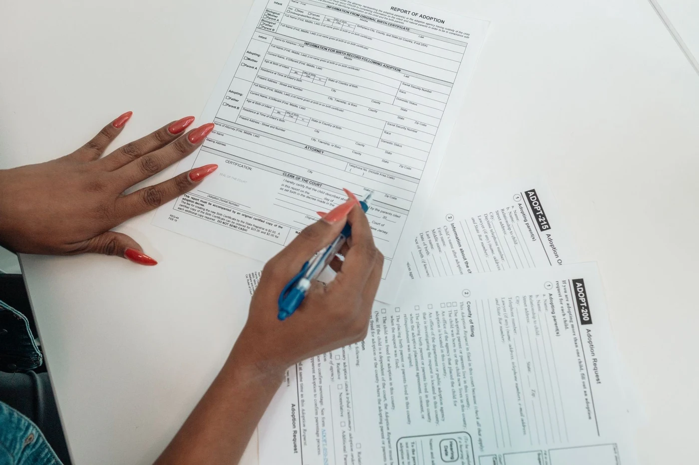 Hands filling out paperwork and account forms on a desk