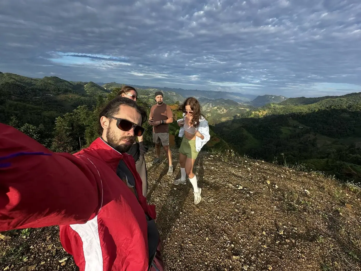 four travelers on a mountain ridge overlooking Ha Giang valleys